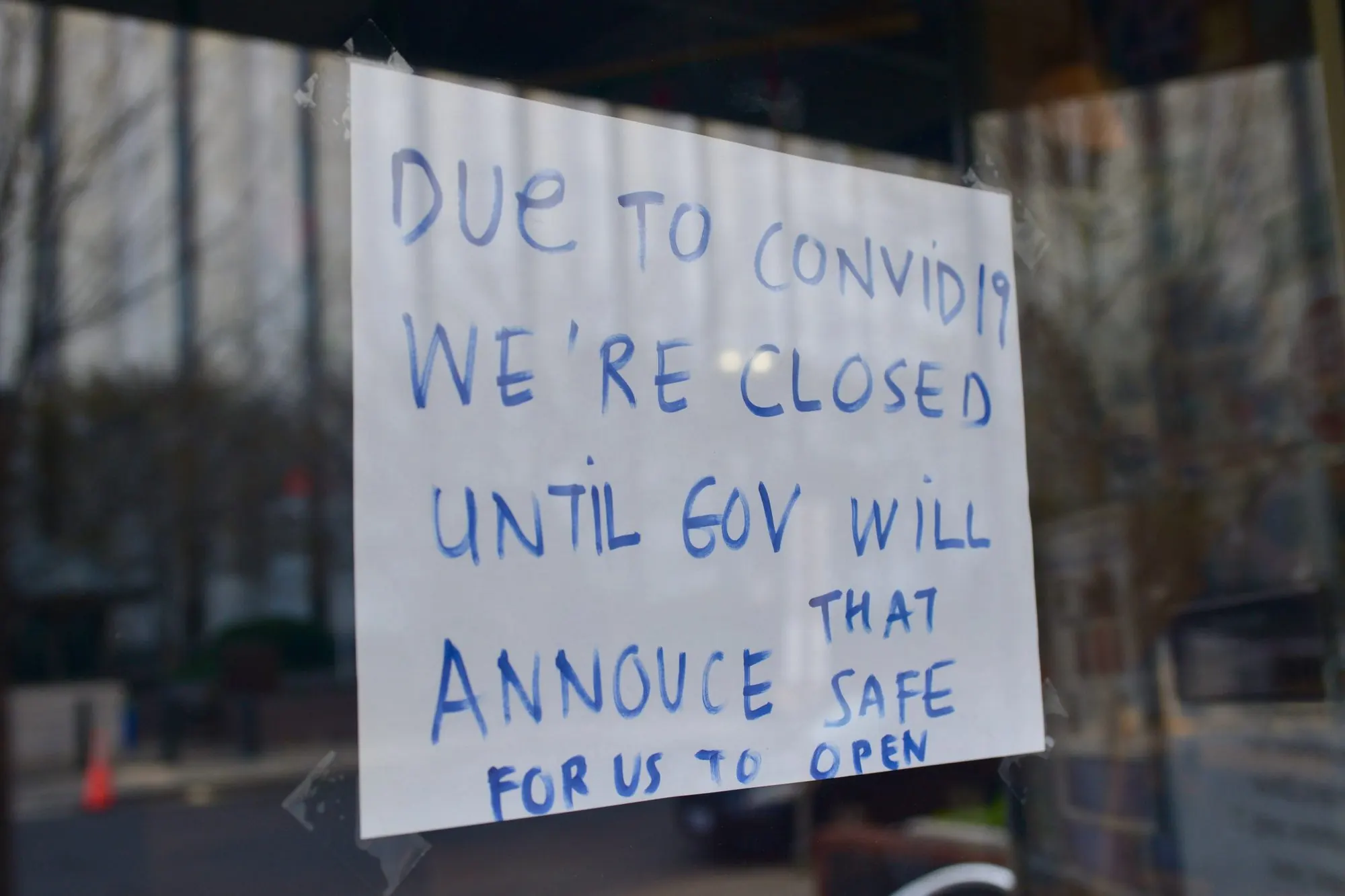 A handwritten sign in a shop window announcing a COVID-19 closure