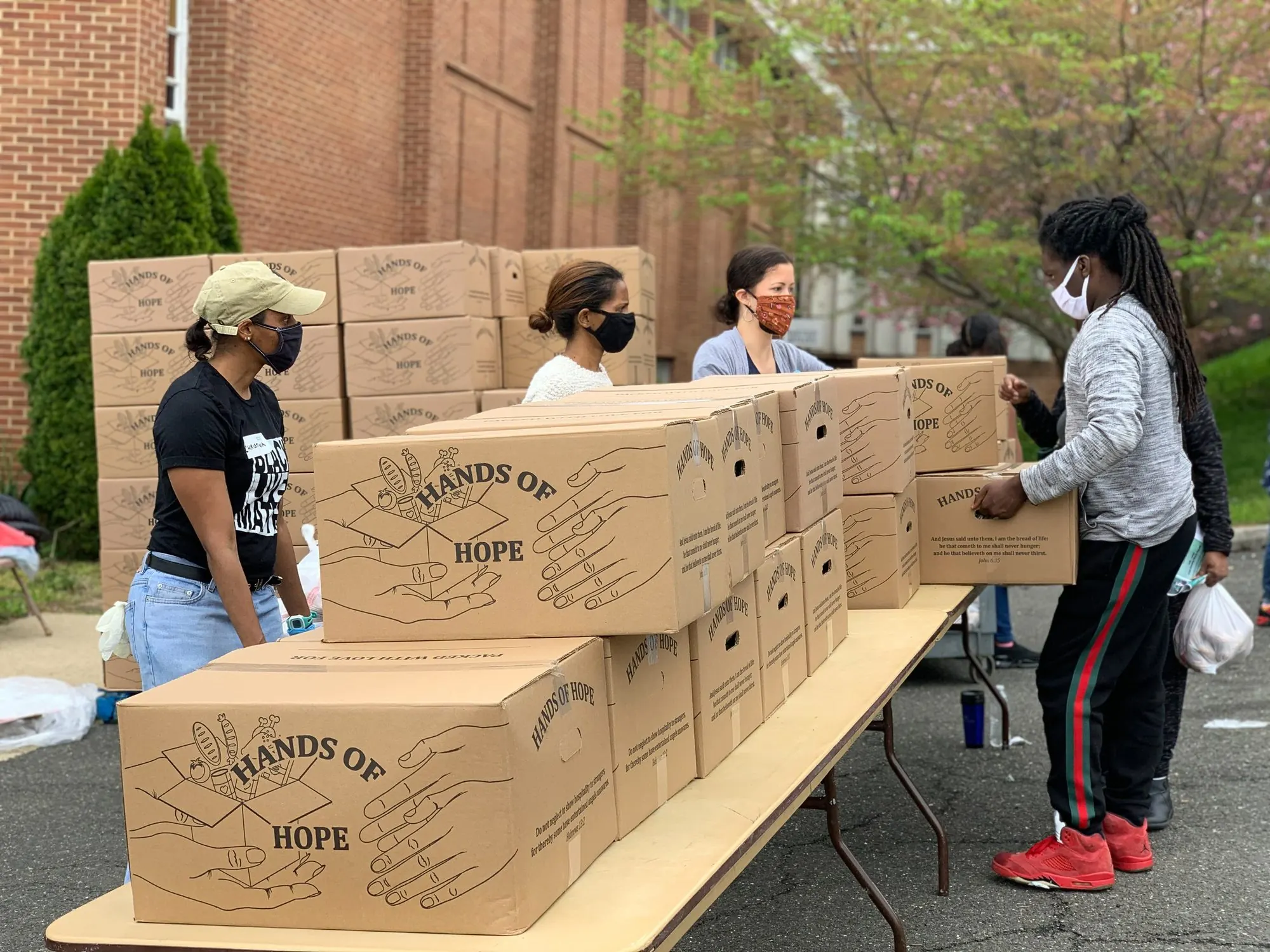Masked volunteers distributing Hands of Hope food boxes