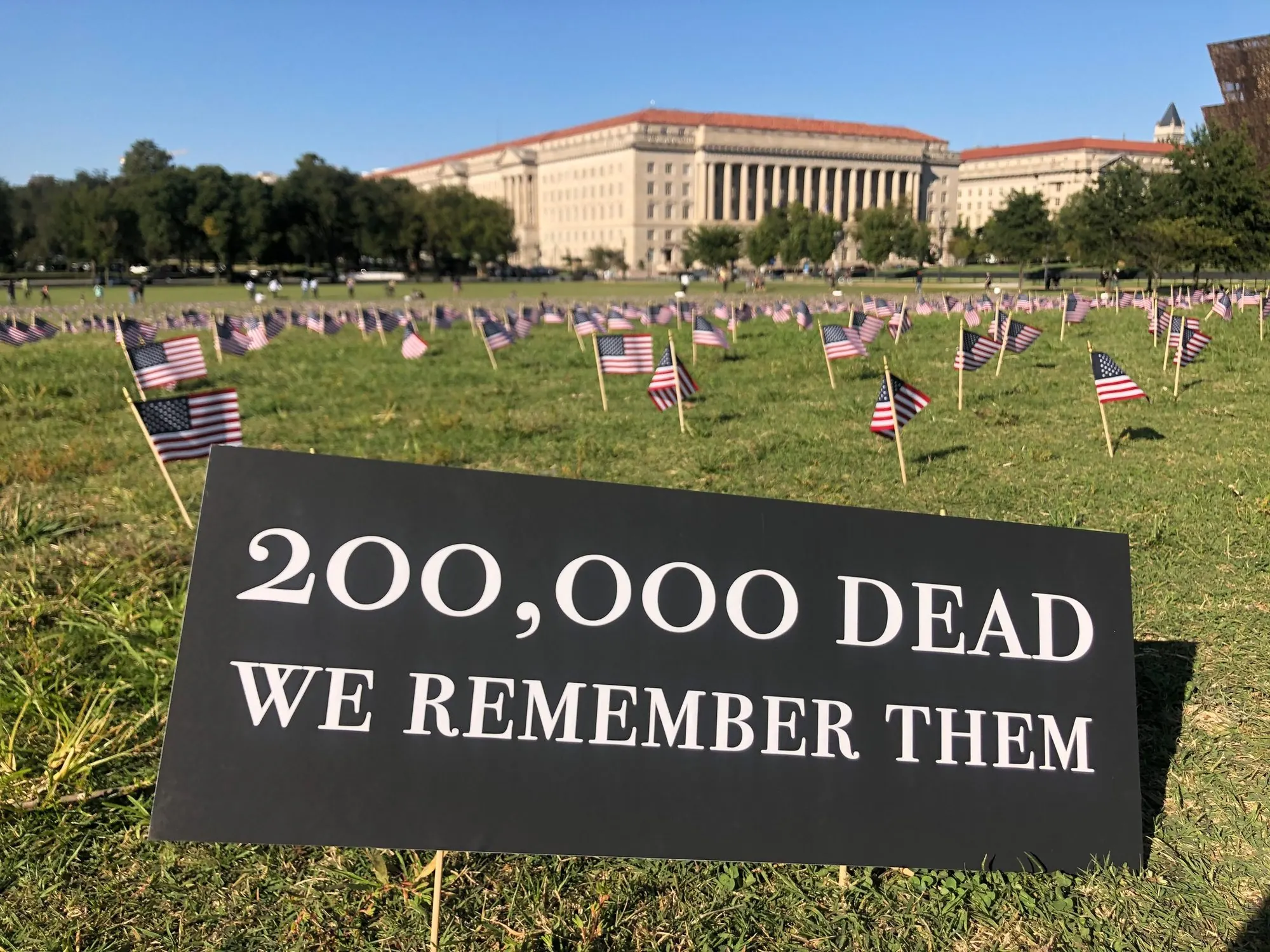 A field of American flags and a sign reading 200,000 dead, we remember them