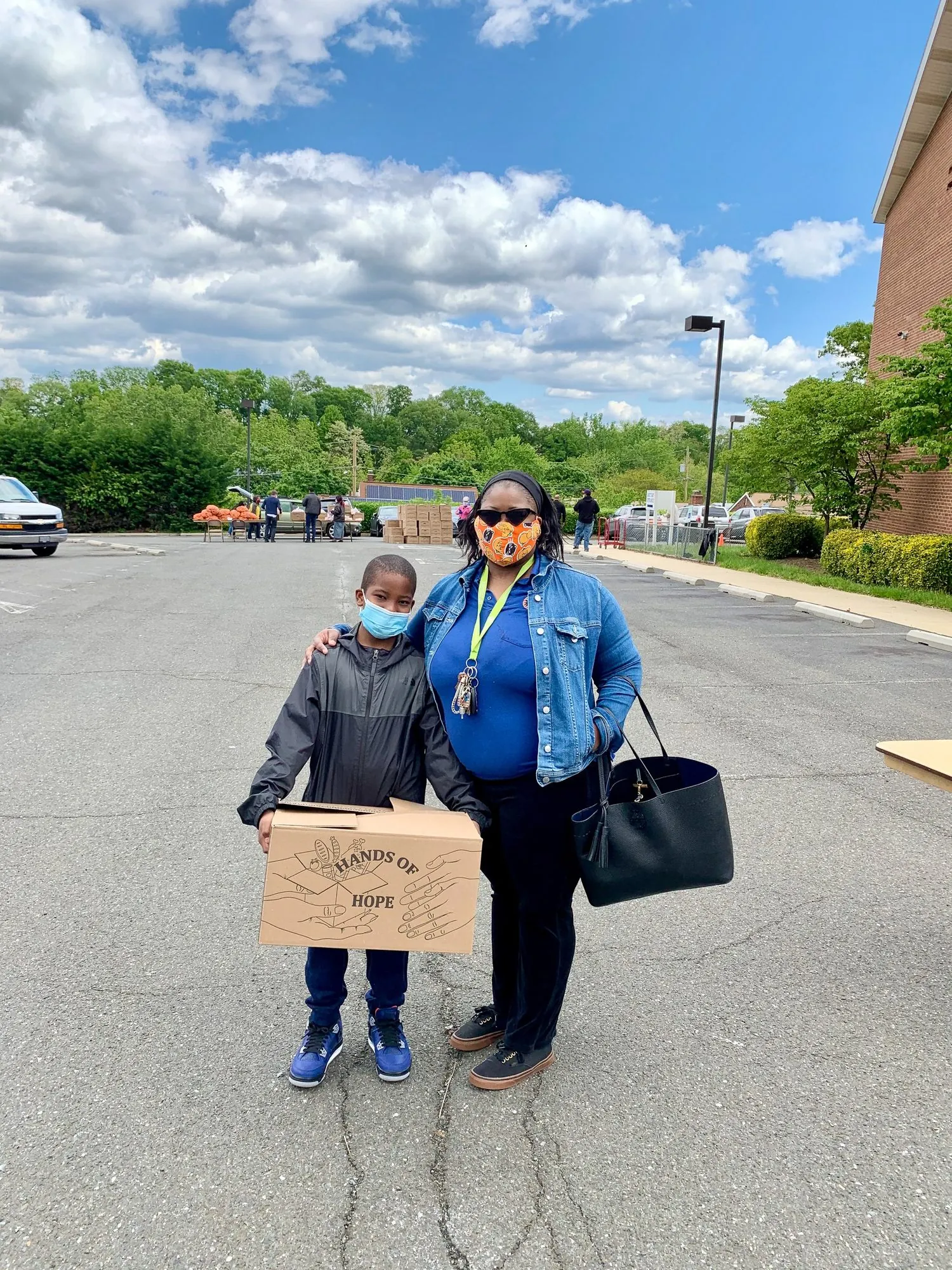 A masked woman and child holding a Hands of Hope food box